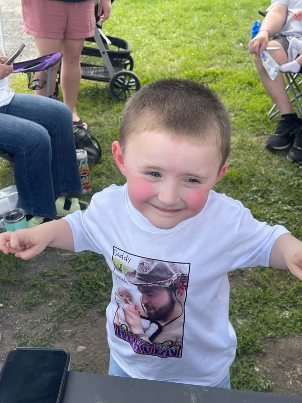 Matt's son Noah smiling in a Daddy and Noah Scoop of Heaven 2026 shirt with a photo of Matt holding him as a baby